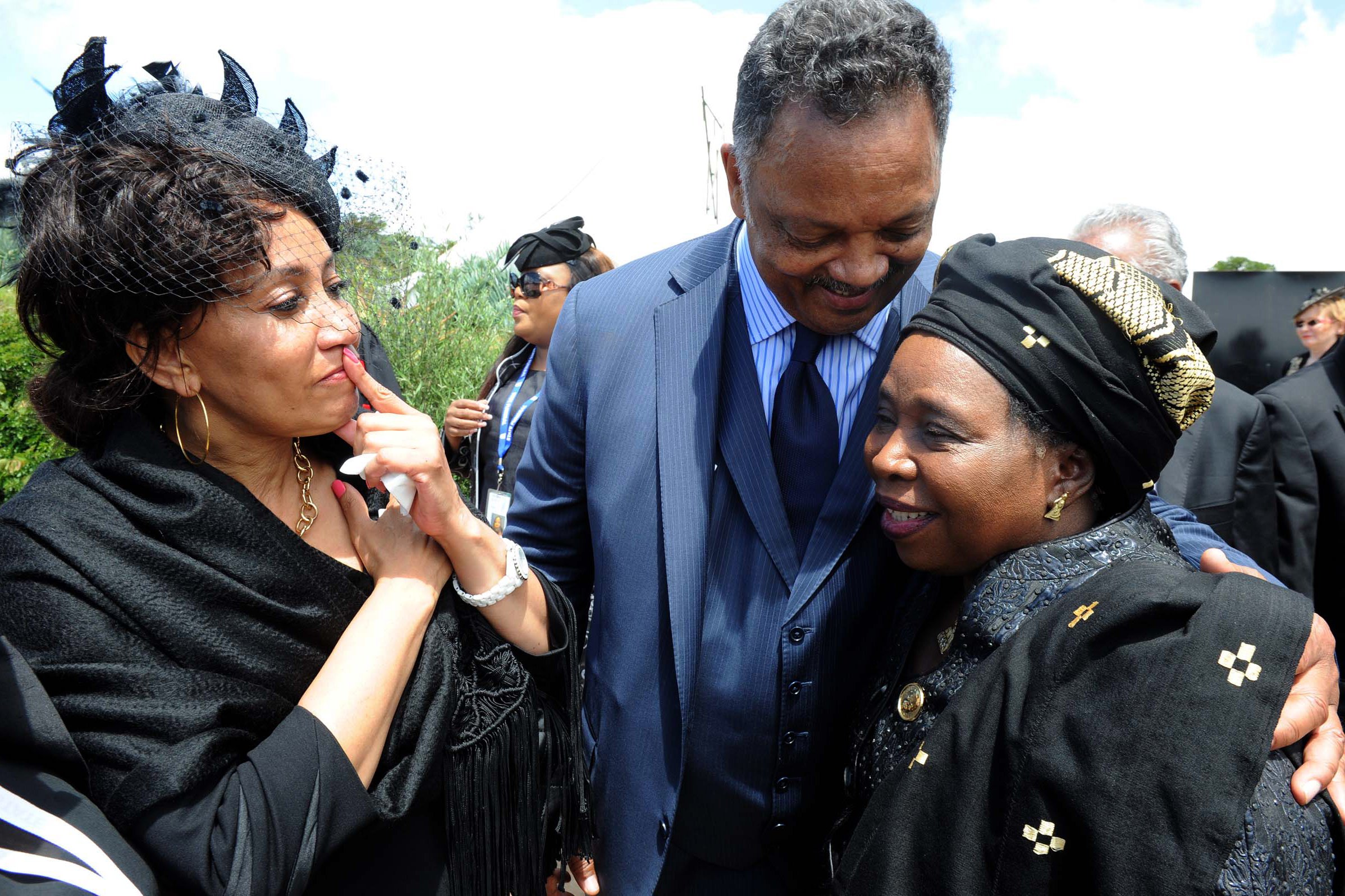 O pastor Jesse Jackson abraçando a ativista anti-apartheid e ex-esposa de Jacob Zuma, Nkosazana Dlamini Zuma (direita) e a ministra da Função Pública, Lindiwe Sisulu (esquerda),  durante o funeral de Mandela 