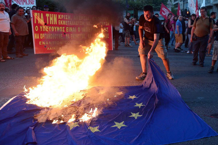 Ativista anti-UE queima bandeira da união em frente ao escritório da Comissão Europeia em Atenas, em 2 de julho 