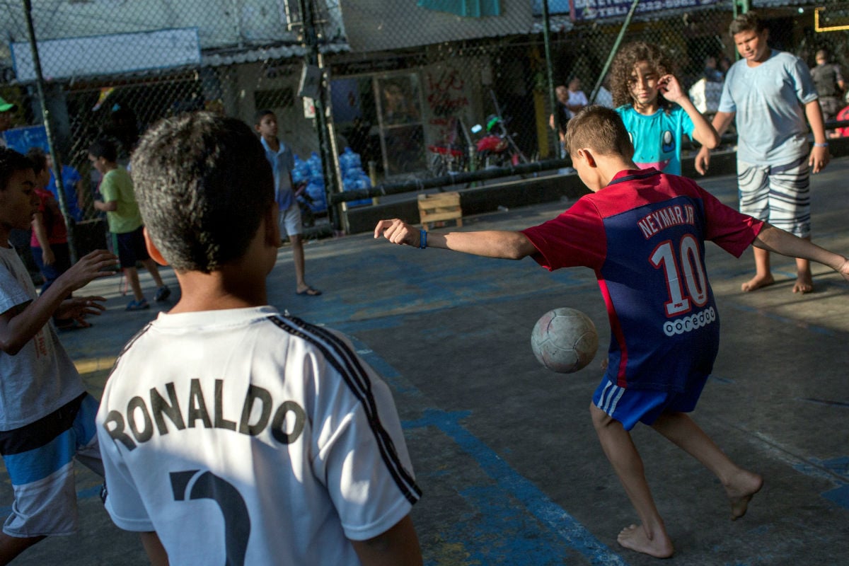 Crianças jogam futebol em quadra na entrada da Rocinha. A violência afeta o cotidiano da comunidade e dos bairros chiques ao redor 