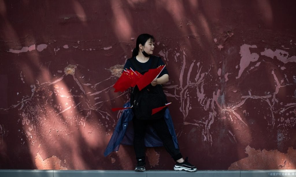 CHINA: Mulher vende bandeiras nacionais perto da Praça Tiananmen enquanto as pessoas se reúnem para o Dia do Trabalho, em Pequim (Foto: FRED DUFOUR/AFP)