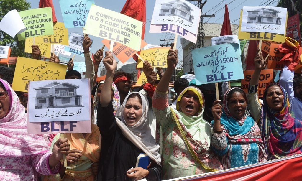 PAQUISTÃO: Funcionários do sindicato paquistanês seguram cartazes e gritam slogans ao marchar durante manifestação em 1º de maio de 2019 em Lahore (Foto: ARIF ALI/AFP)