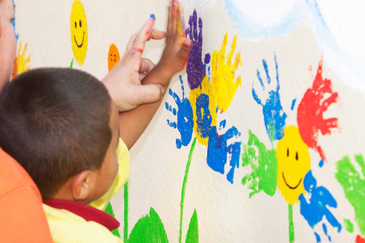 Criança pintando muro||