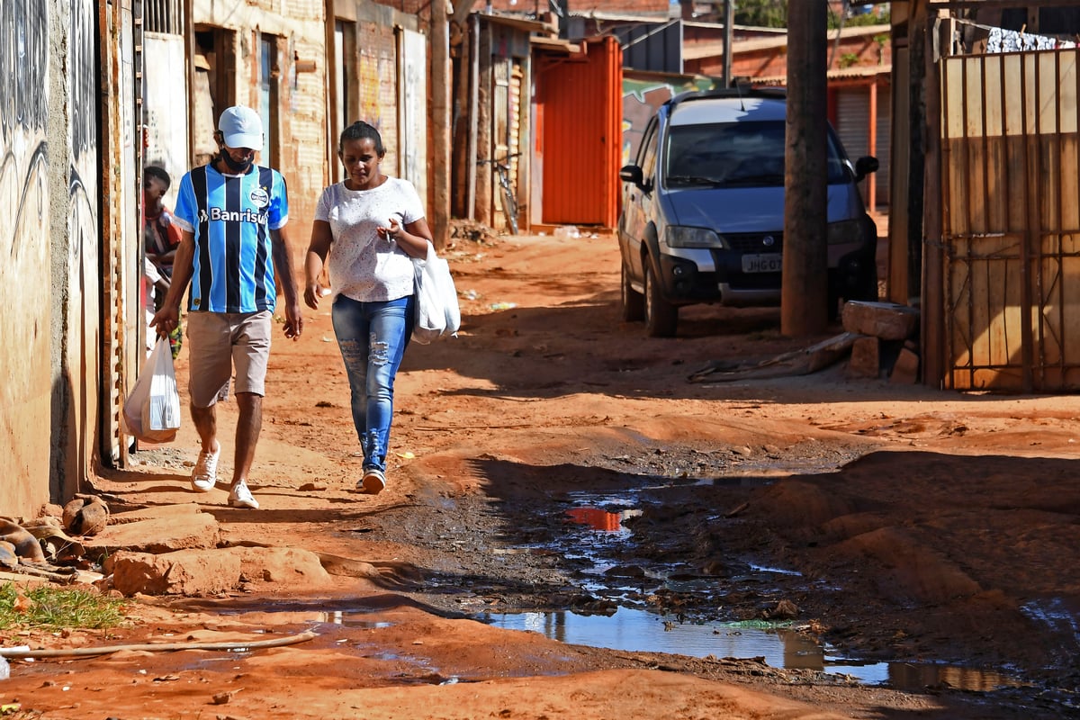 Pessoas caminham em rua com água de esgoto de Guará, a 20 km de Brasília. (Foto: Evaristo Sá/AFP)  (Foto: Evaristo Sá/AFP)