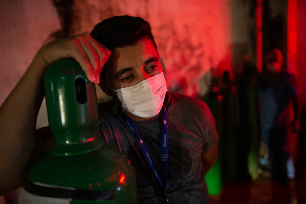 Um homem segura um tanque de oxigênio. Foto: Michael DANTAS / AFP 