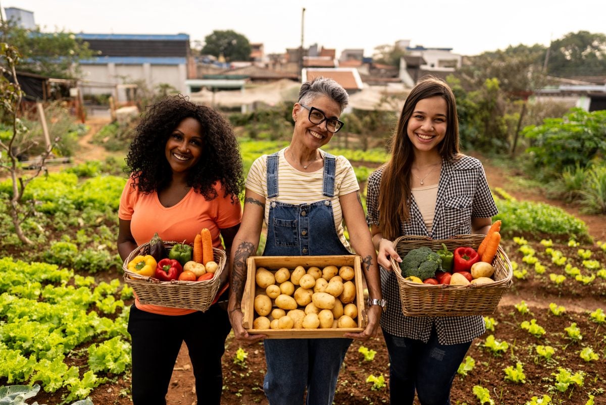 Portrait of farmers carrying fruit and vegetables baskets on a community garden 